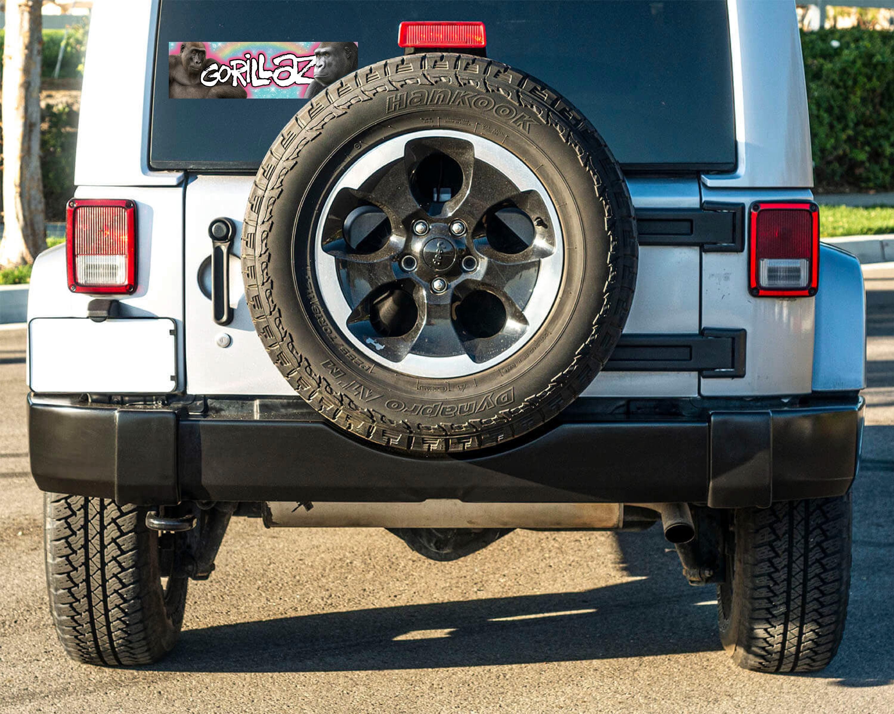 Back view of a vehicle with a spare tire mounted on the back, featuring a Gorillaz sticker.