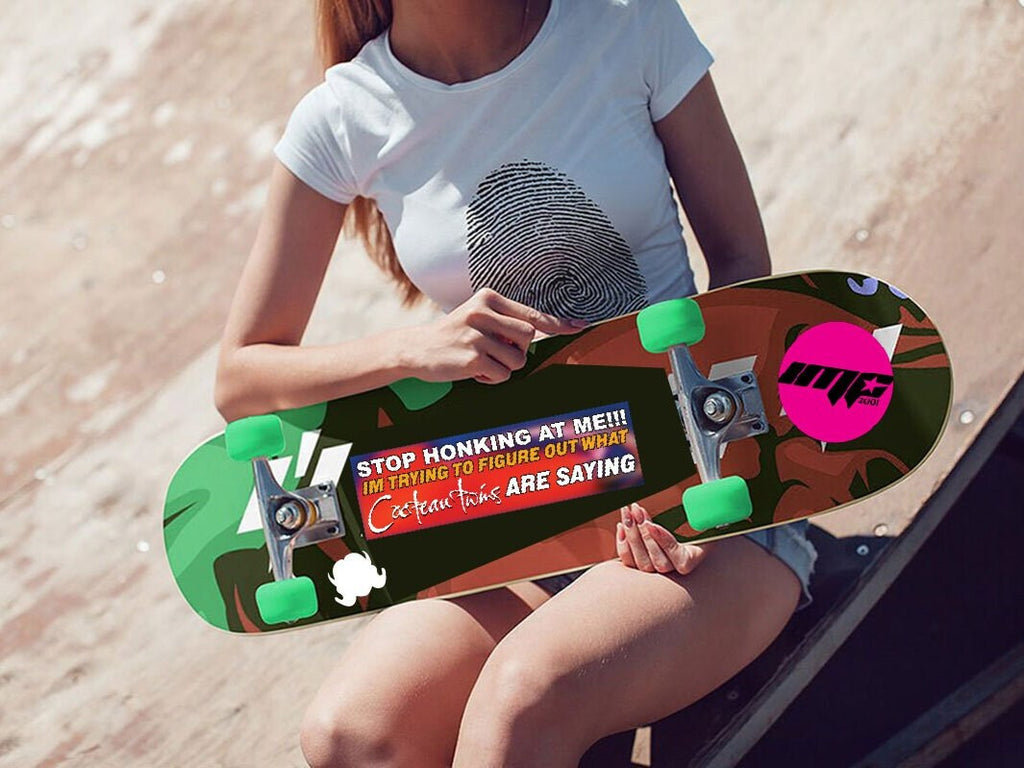 Person holding a colorful skateboard with text on a beach