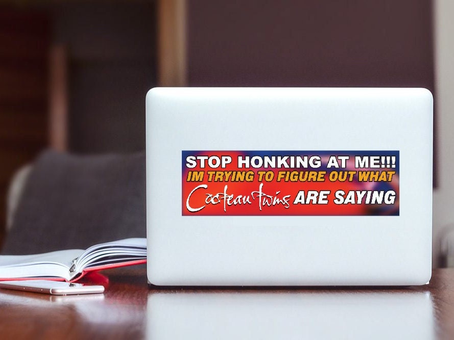 Laptop with a humorous sticker on a wooden surface