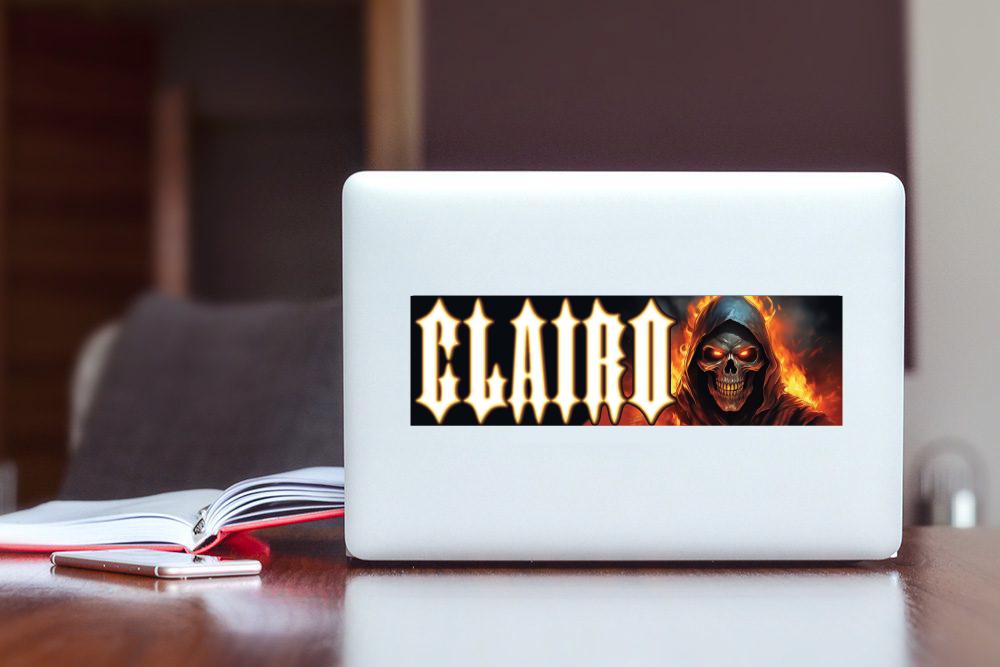 Laptop with a 'Clairo' logo featuring a skull on a wooden table.