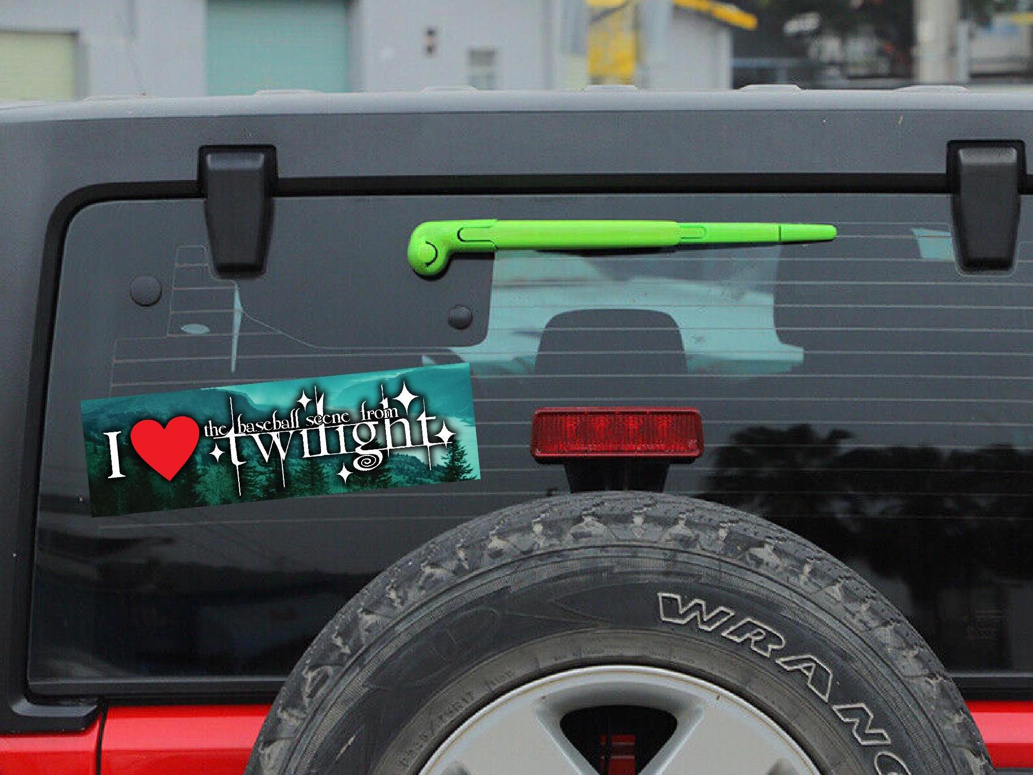 Back of a black Jeep Wrangler with 'I ❤️ Twilight' bumper sticker and green tool on tailgate.