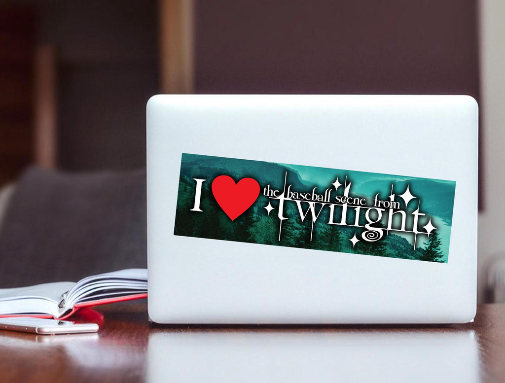 White laptop with a 'I ❤️ the baseball scene from Twilight' sticker on a wooden surface.