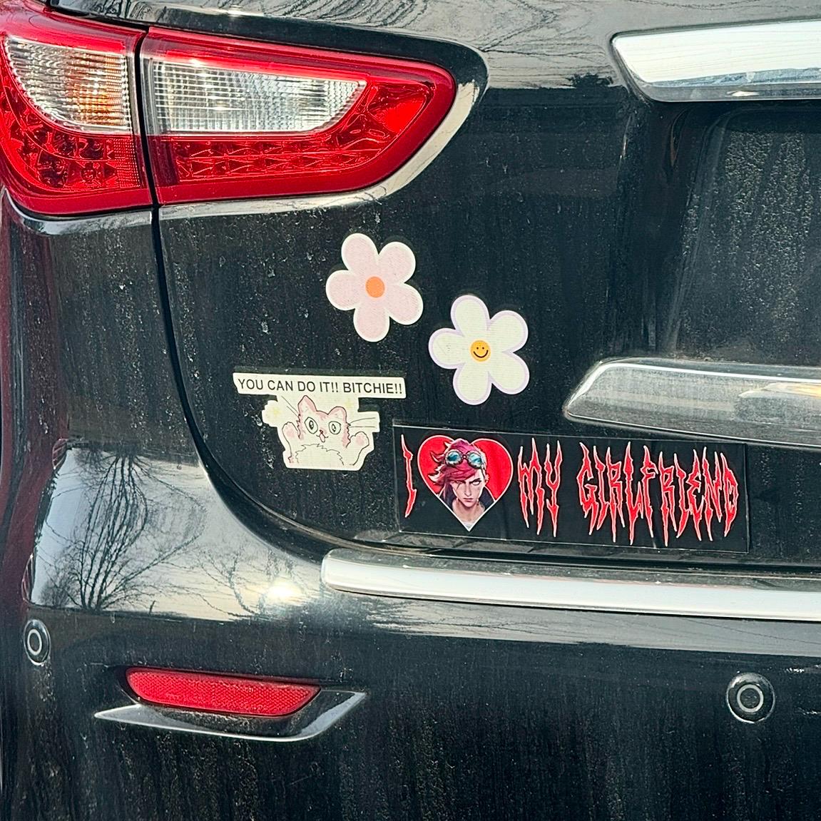Car back with stickers including a heart and text design.
