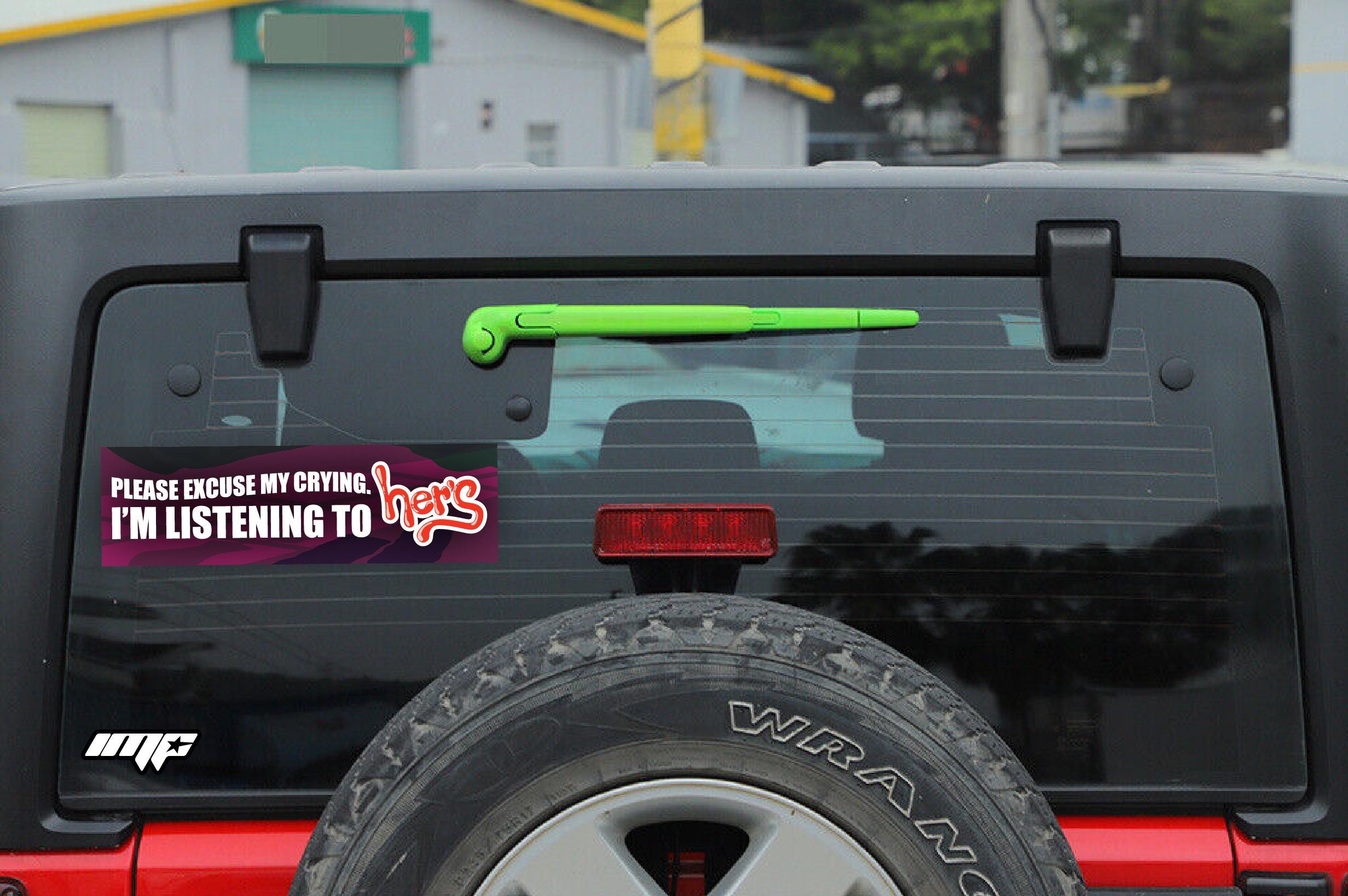 Back of a black Jeep with a humorous license plate sticker and visible 'MP' logo.